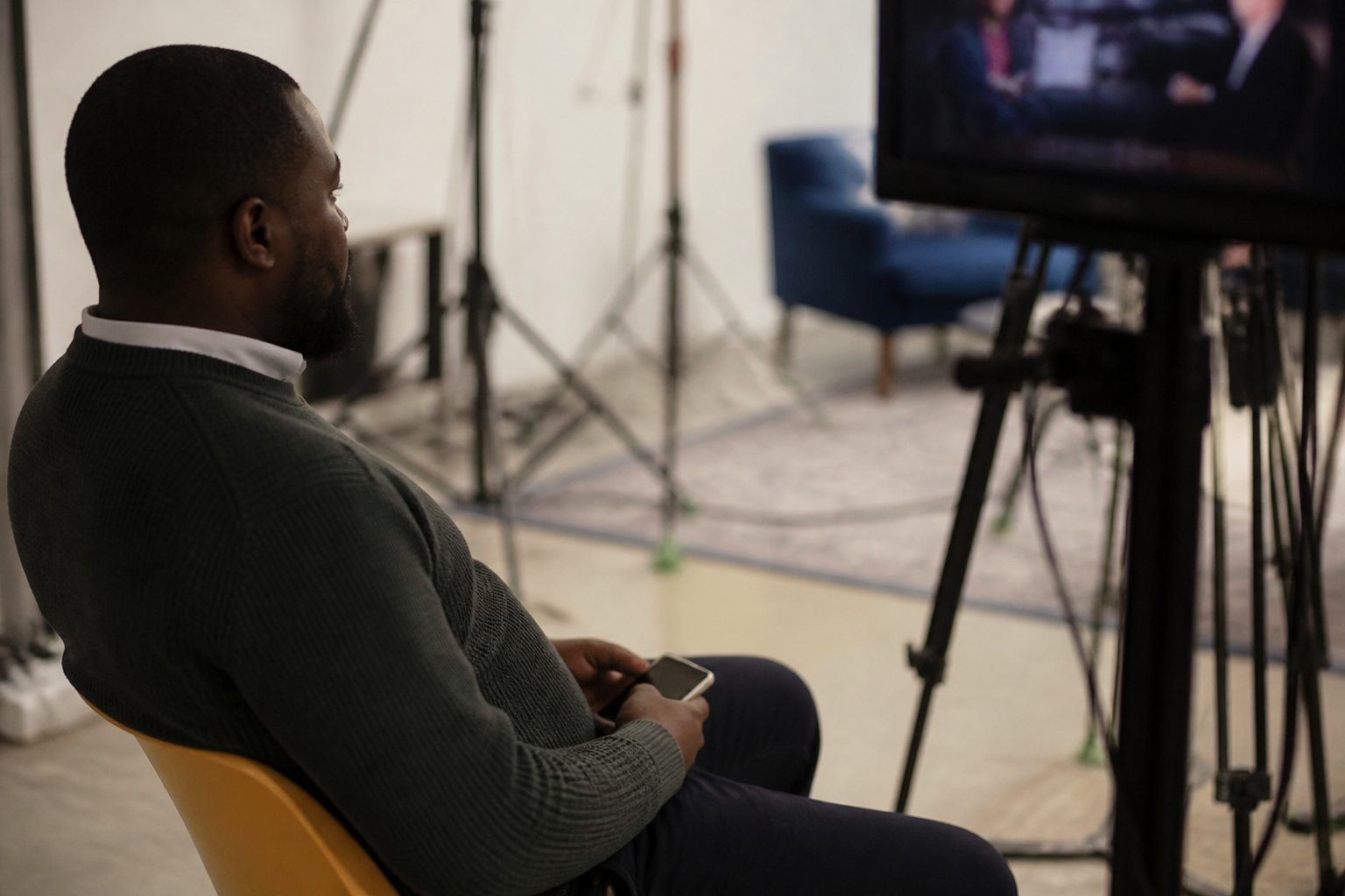 Candidat tenant un telephone, regardant ecran television en studio.
